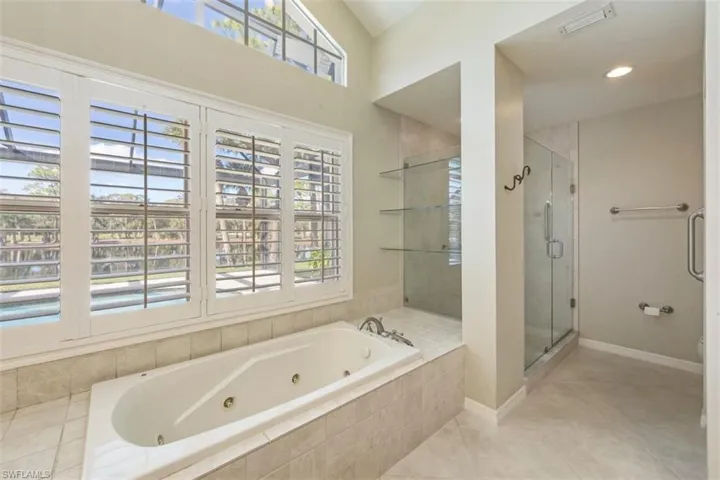 Full bath with a stall shower, a whirlpool tub, plenty of natural light, and light tile patterned floors
