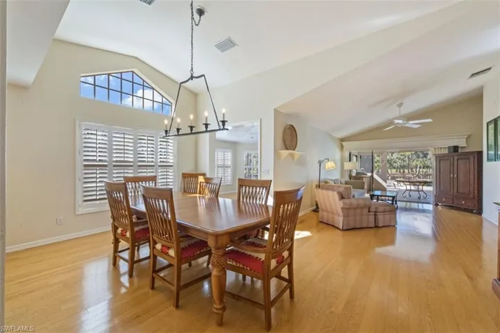Dining room featuring healthy amount of natural light, light wood-style floors, high vaulted ceiling, ceiling fan, and a chandelier