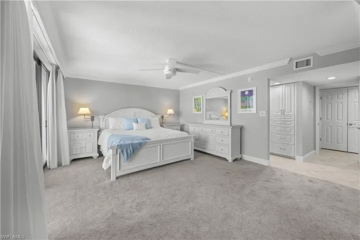 Primary bedroom with light gray carpet and white furnishings.