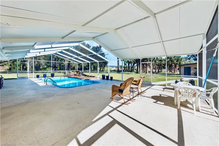 View of pool with a yard, glass enclosure, and a patio area