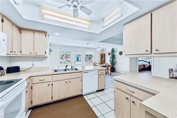 Kitchen featuring kitchen peninsula, sink, white appliances, and light brown cabinets