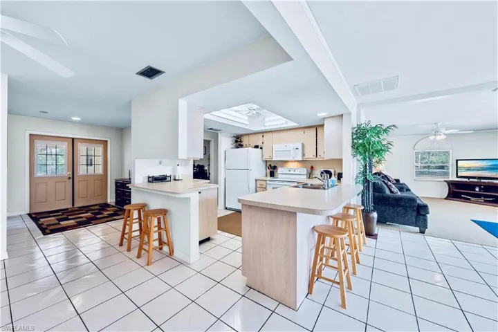 Kitchen with kitchen peninsula, ceiling fan, a breakfast bar, and white appliances