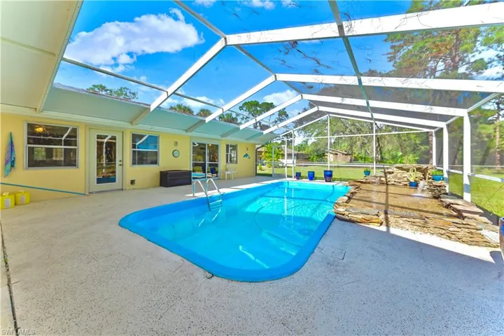 View of swimming pool featuring glass enclosure and a patio