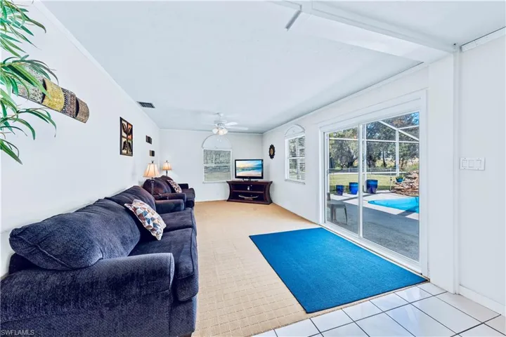 Living room featuring ceiling fan, light tile patterned floors, and crown molding