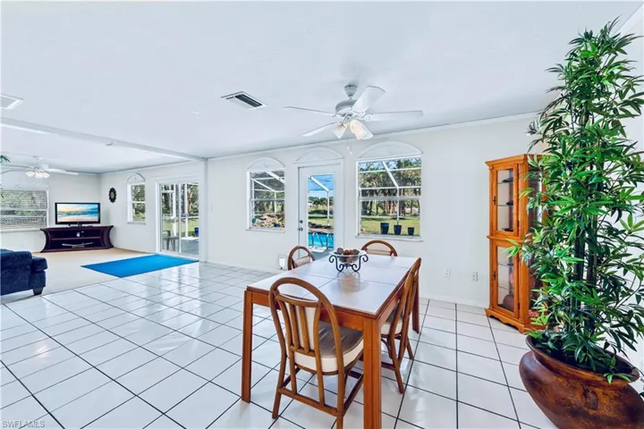 Dining area with plenty of natural light, light tile patterned flooring, ornamental molding, and ceiling fan