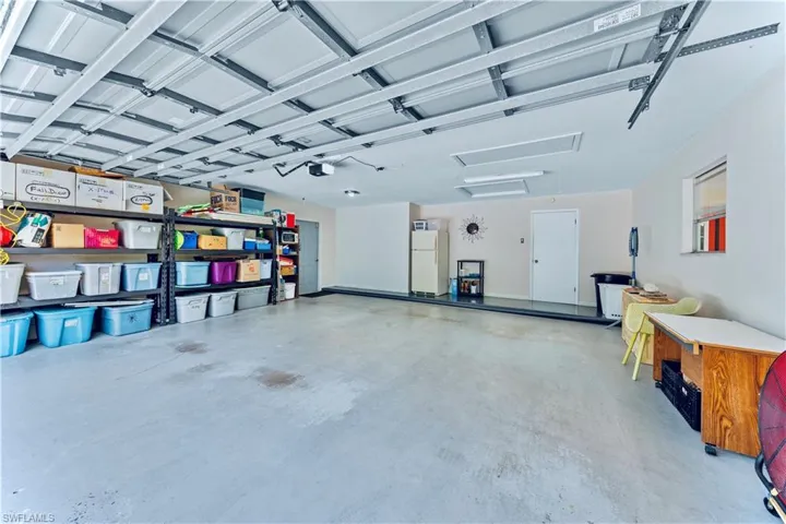 Garage with white refrigerator and a garage door opener
