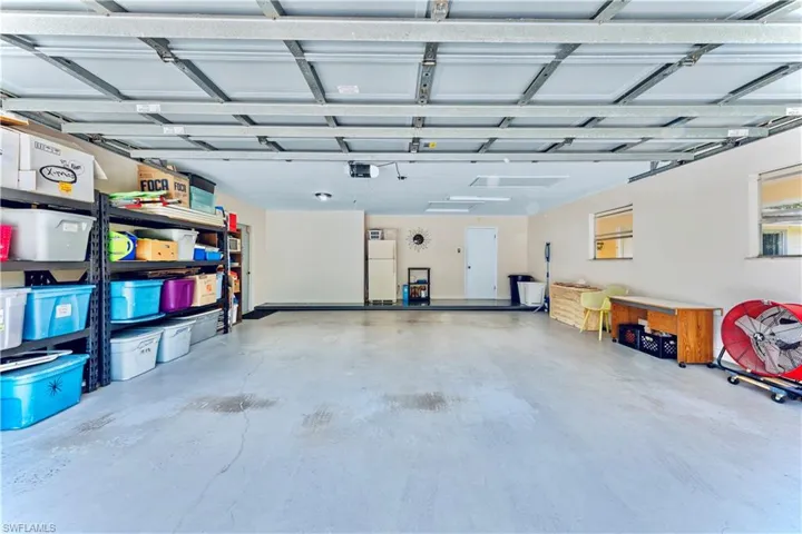 Garage featuring a garage door opener and white refrigerator