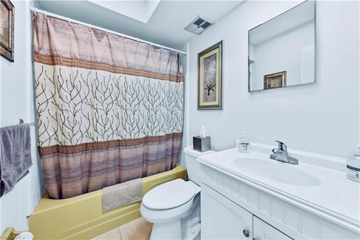 Full bathroom featuring toilet, shower / bath combination with curtain, vanity, and tile patterned floors