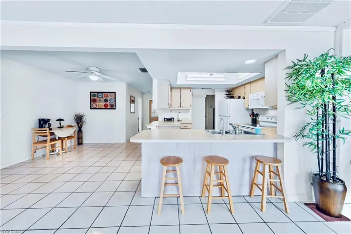Kitchen featuring a kitchen breakfast bar, kitchen peninsula, light tile patterned flooring, and white appliances