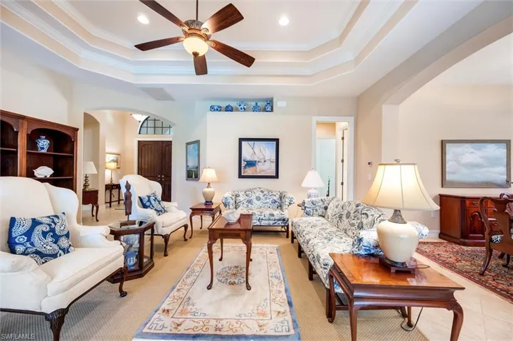 Living room with ceiling fan, ornamental molding, arched walkways, and recessed lighting