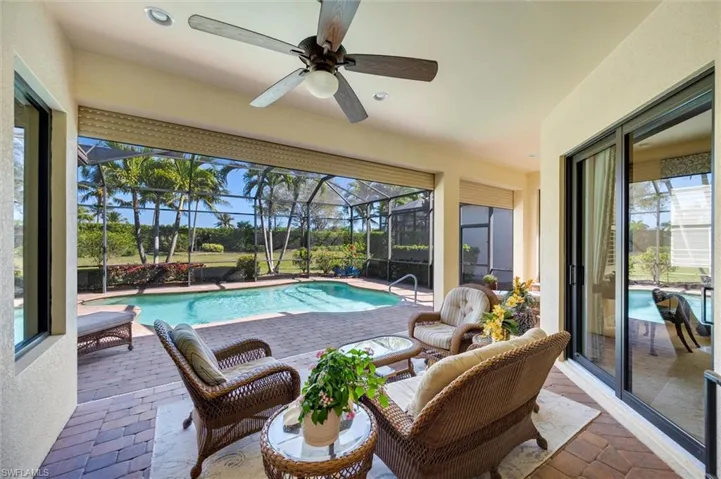 Swimming pool with a patio area, glass enclosure, and a sunroom