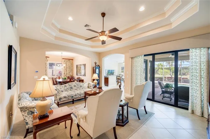 Living area featuring a ceiling fan, ornamental molding, arched walkways, and light tile patterned flooring
