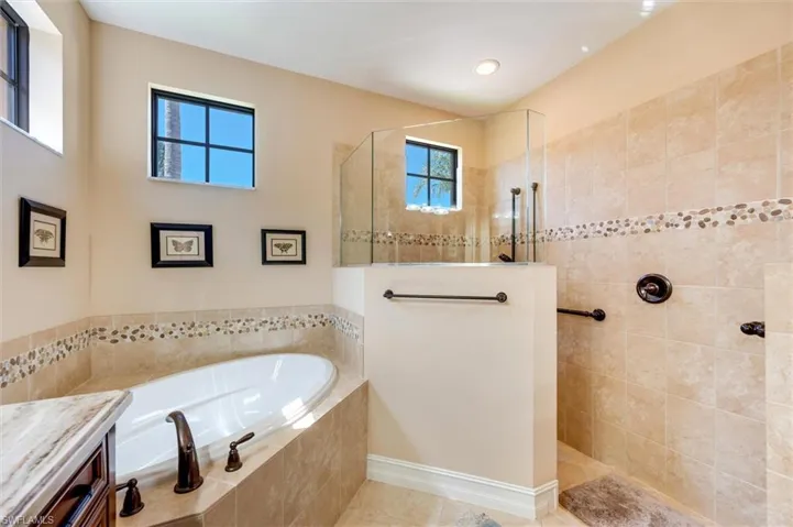 Bathroom featuring a garden tub, a walk in shower, vanity, and light tile patterned floors