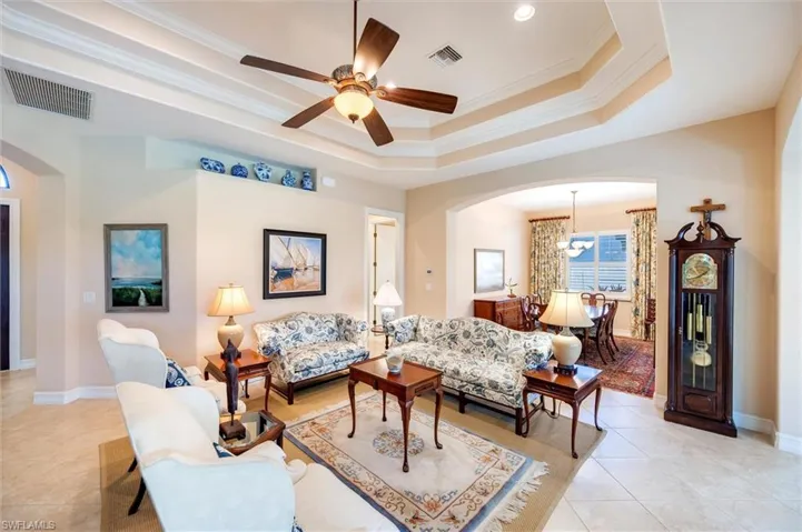 Living room with arched walkways, crown molding, a ceiling fan, and light tile patterned flooring