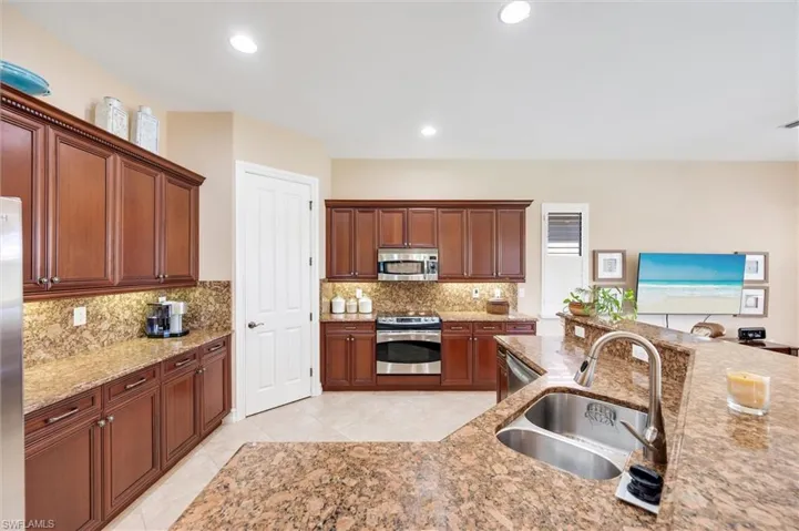 Kitchen featuring stainless steel appliances, light stone counters, recessed lighting, backsplash, and wood finish cabinetry