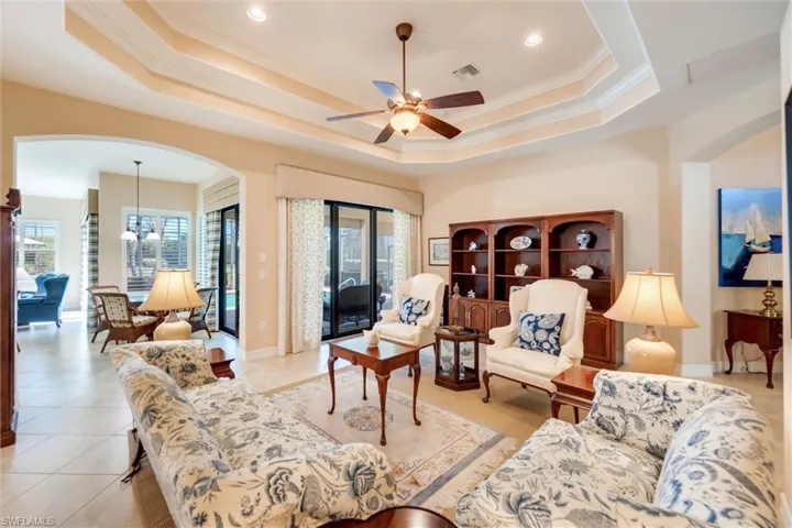 Living area with arched walkways, plenty of natural light, crown molding, a ceiling fan, and a chandelier