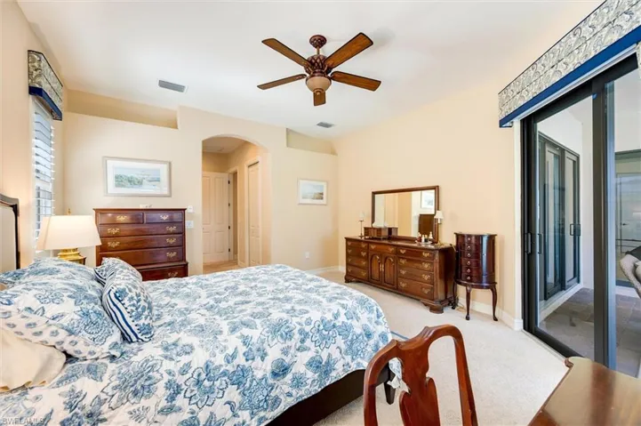 Bedroom featuring access to exterior, light carpet, a ceiling fan, and arched walkways