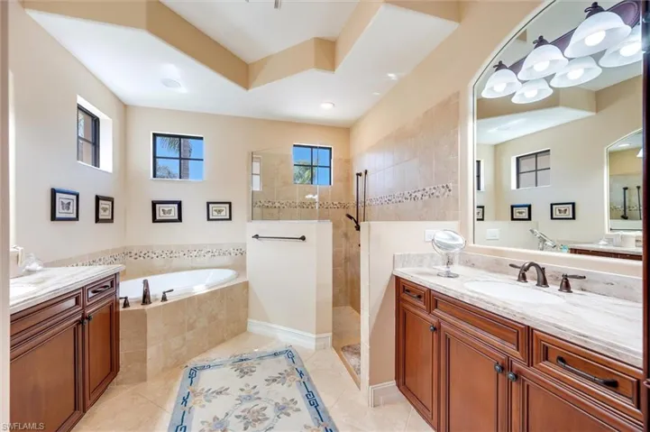 Bathroom featuring a garden tub, two vanities, walk in shower, recessed lighting, and light tile patterned floors