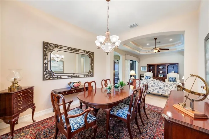 Dining area featuring hanging lights, a ceiling fan, crown molding, a raised ceiling, and arched walkways