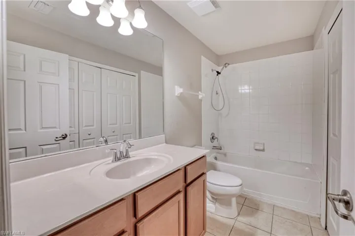 Bathroom featuring toilet, tile patterned flooring, vanity, shower / bathtub combination, and a chandelier