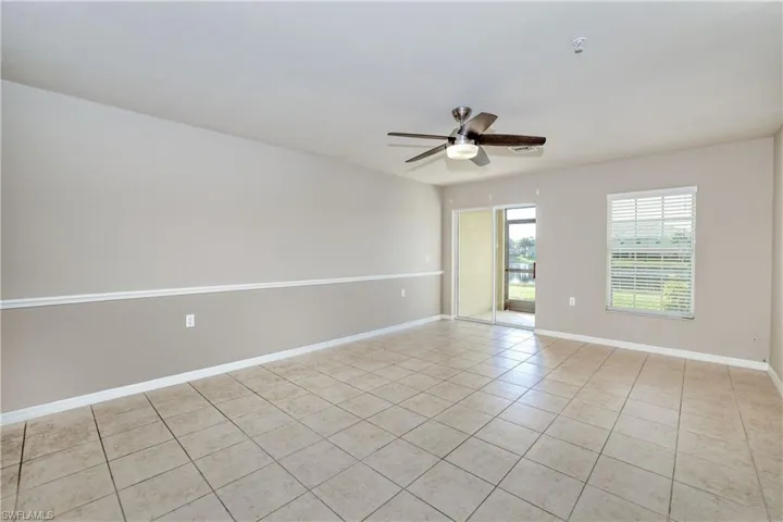 Empty room featuring light tile patterned flooring, ceiling fan, baseboards, and a pendent fire sprinkler