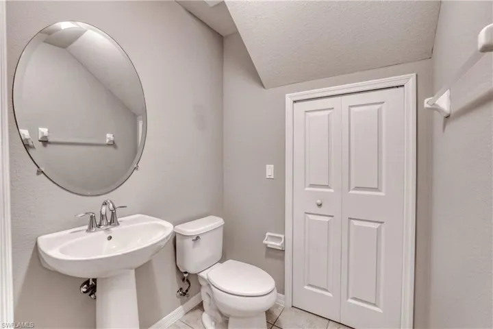 Bathroom featuring tile patterned floors, toilet, baseboards, and a textured ceiling