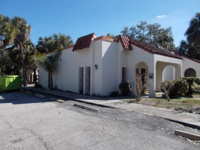 View of front facade featuring stucco siding, a tiled roof, and uncovered parking