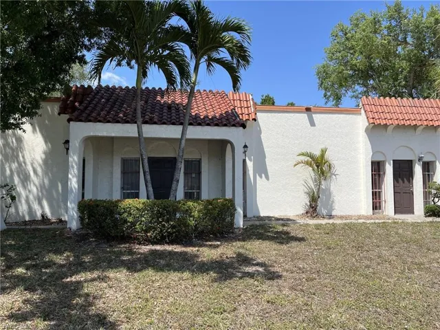 Back of house featuring a tile roof, a yard, and stucco siding