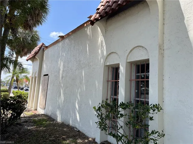View of side of property featuring a tile roof and stucco siding