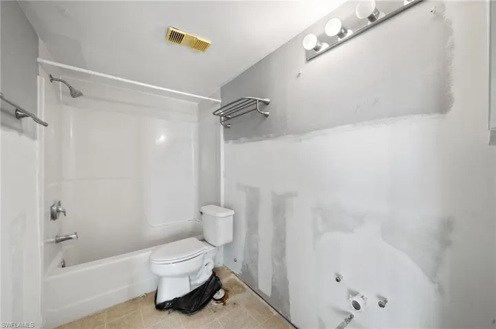 Bathroom with toilet, bathtub / shower combination, and tile patterned floors