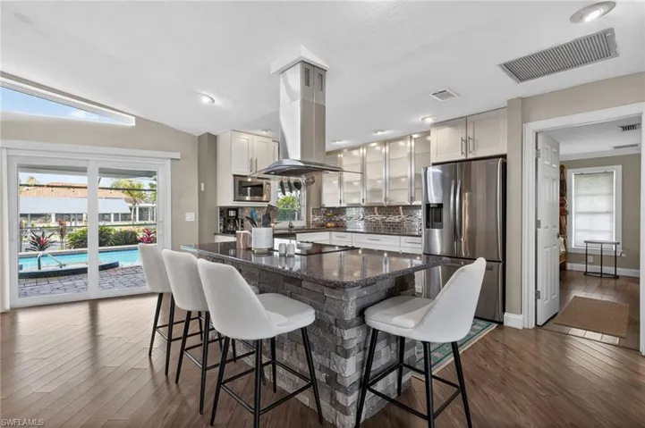 Kitchen featuring stainless steel appliances, glass fronted cabinets, island exhaust hood, and a kitchen island