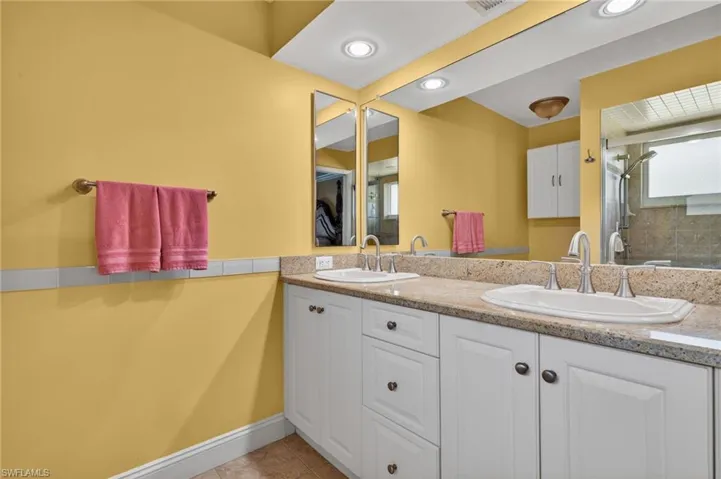 Full bath with double vanity, l shower, light tile floors, and recessed lighting