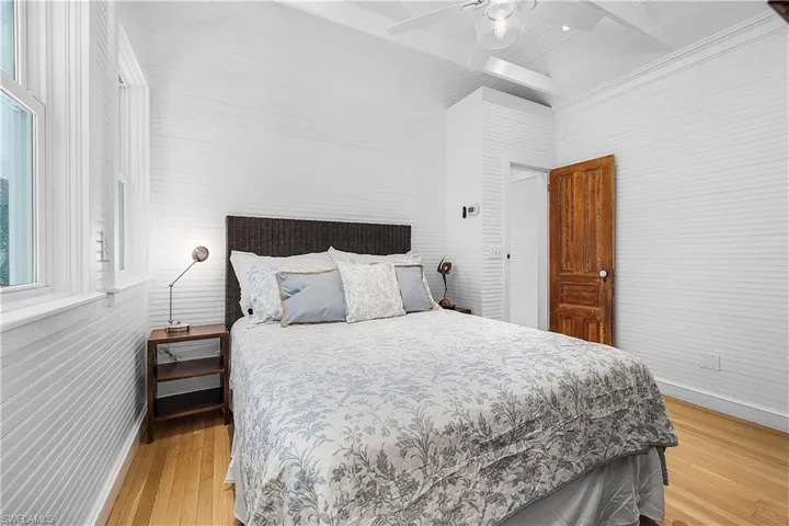 Bedroom featuring ceiling fan, vaulted ceiling with beams, and light hardwood / wood-style floors