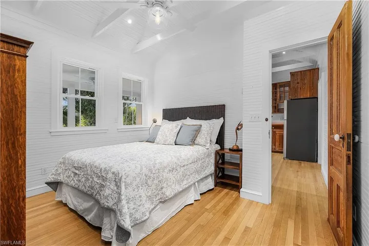 Bedroom featuring beamed ceiling, stainless steel refrigerator, ceiling fan, and light hardwood / wood-style floors