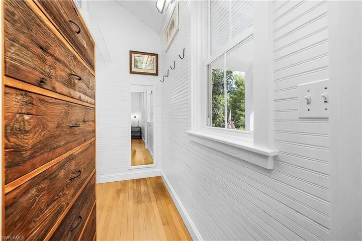 Hall featuring light wood-type flooring and wooden walls