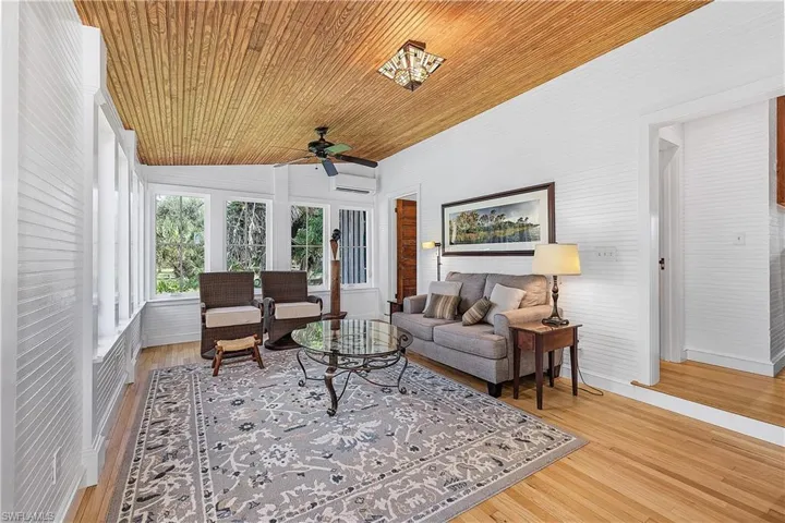 Living room with wooden ceiling, a wall mounted AC, ceiling fan, and light hardwood / wood-style floors