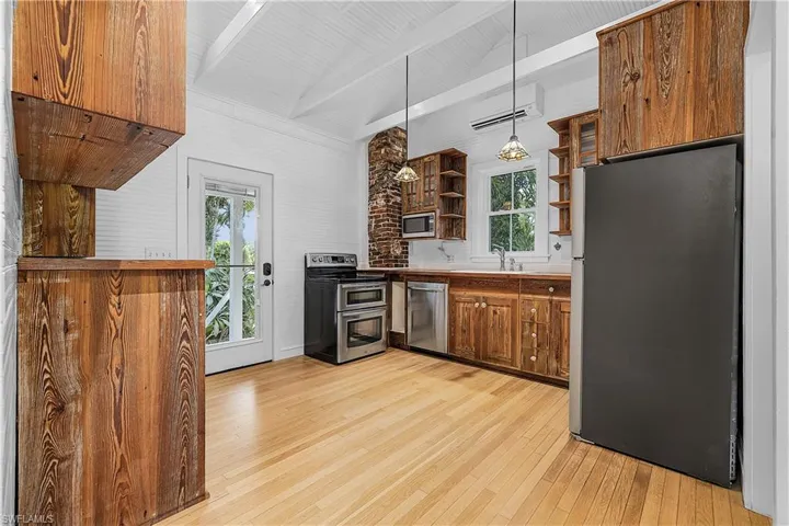 Kitchen featuring hanging light fixtures, a wealth of natural light, stainless steel appliances, and vaulted ceiling with beams