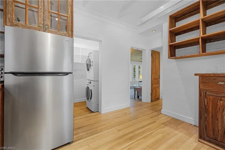 Kitchen with stacked washer / dryer, stainless steel fridge, and light wood-type flooring