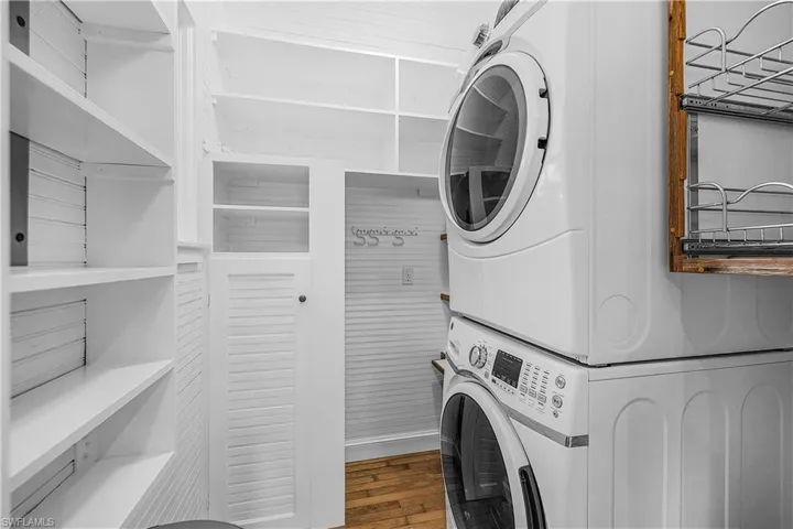 Laundry room featuring stacked washer and dryer and hardwood / wood-style flooring