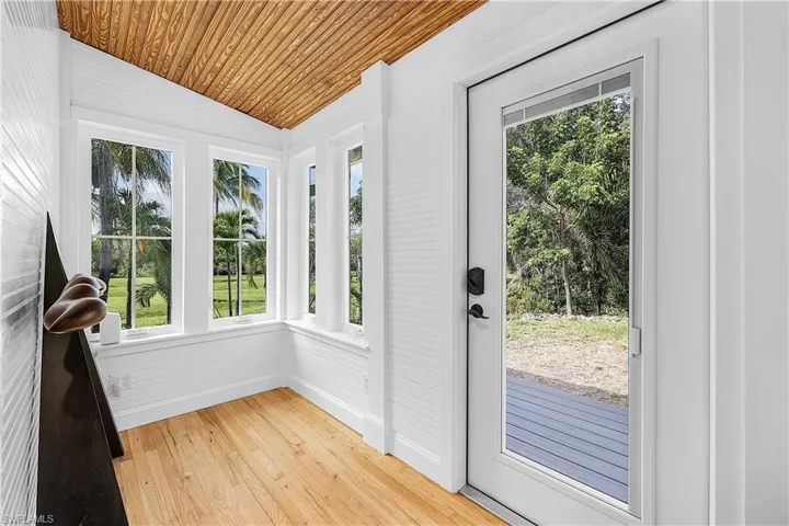 Doorway featuring wooden ceiling, vaulted ceiling, a healthy amount of sunlight, and light hardwood / wood-style floors