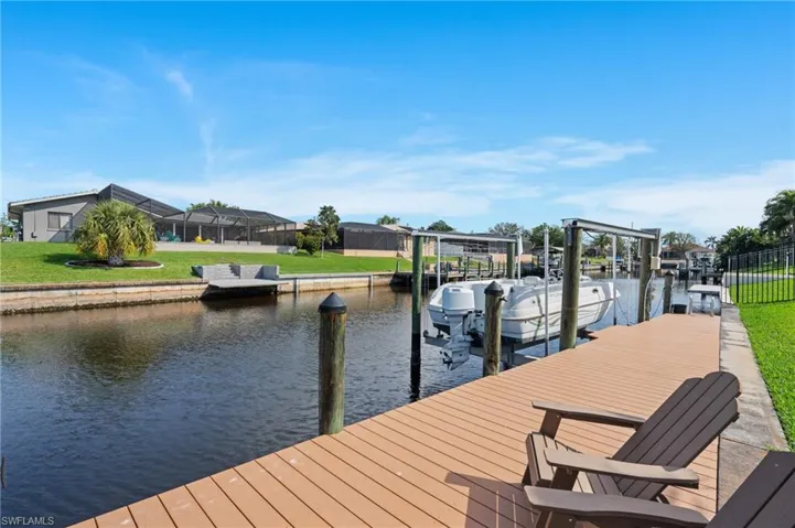View of dock with a lawn, a water view, and a lanai