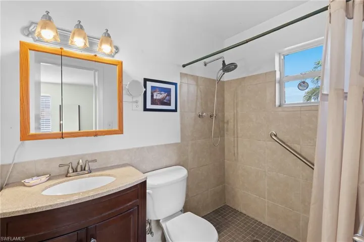 Bathroom featuring toilet, vanity, and a shower with curtain