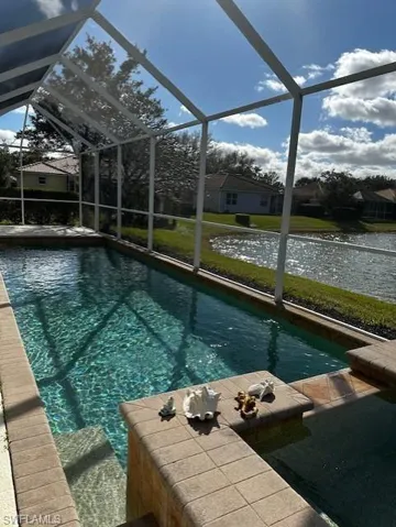 Swimming pool featuring a sunroom, a lanai, a water view, a residential view, and a lawn