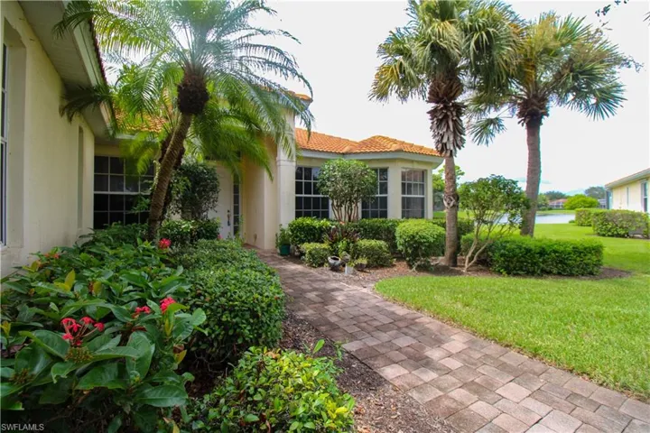 Entrance to property featuring stucco siding, a lawn, and a tiled roof