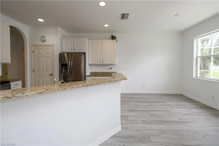 Kitchen with appliances with stainless steel finishes, light stone countertops, arched walkways, recessed lighting, and light wood-style flooring