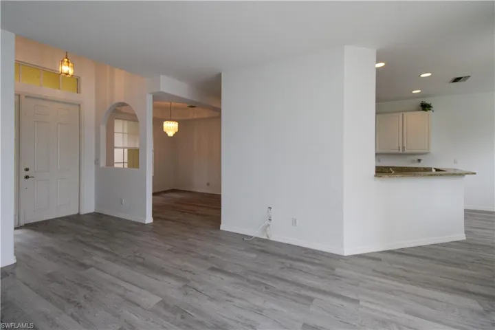 Unfurnished living room featuring light wood-type flooring and arched walkways