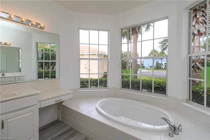 Full bath with vanity, a garden tub, and plenty of natural light
