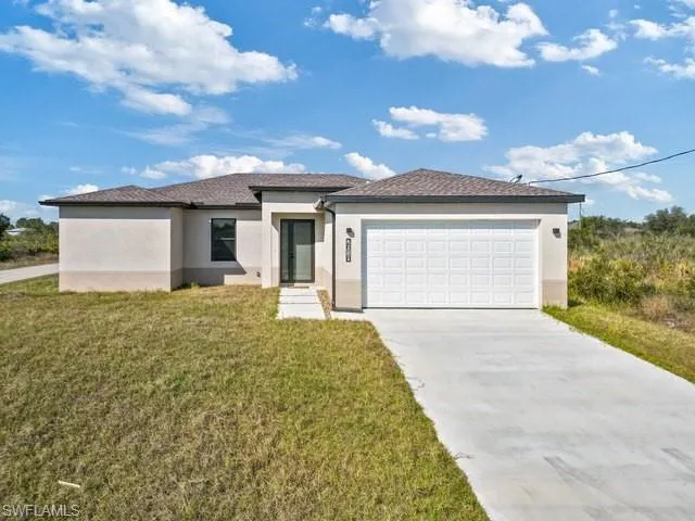 Prairie-style house featuring stucco siding, concrete driveway, a front lawn, and a garage