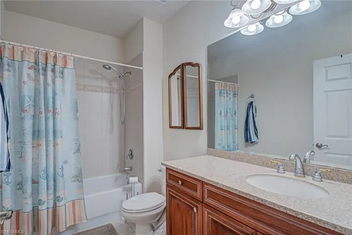 Bathroom featuring shower / bath combo, vanity, a chandelier, and light tile patterned floors