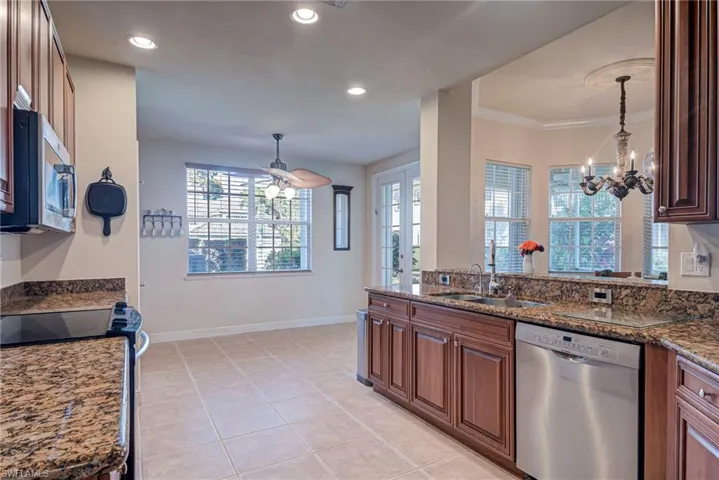 Kitchen with stainless steel appliances, dark stone counters, pendant lighting, a chandelier, and recessed lighting